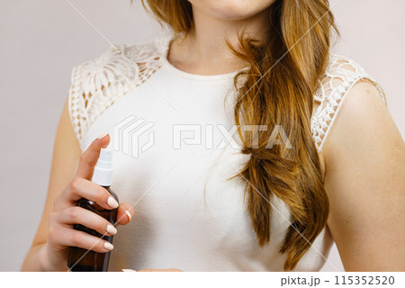 Woman applying hair cosmetic Woman applying hair cosmetic 115352520