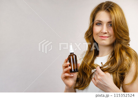 Woman applying hair cosmetic Woman applying hair cosmetic 115352524