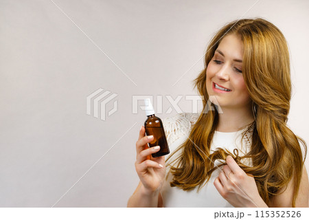 Woman applying hair cosmetic Woman applying hair cosmetic 115352526