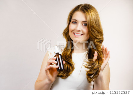 Woman applying hair cosmetic Woman applying hair cosmetic 115352527