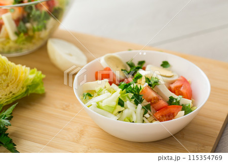 fresh vegetable salad, cabbage, tomatoes in a bowl on a wooden table fresh vegetable salad, cabbage, tomatoes in a bowl on a wooden table 115354769