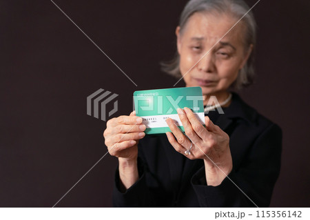 通帳を見て嘆く喪服のシニア女性 115356142