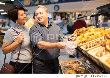 Couple chooses sweet puffs in bakery Couple chooses sweet puffs in bakery 115357179