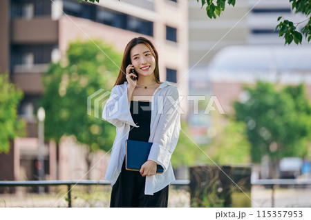 スマホで電話しながら歩く若い女性 スマホで電話しながら歩く若い女性 115357953