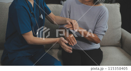 Female caregiver doing regular check-up of senior woman in her home. Female caregiver doing regular check-up of senior woman in her home. 115358405