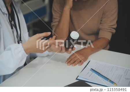 Smiling woman doctor prescribing medicine giving vitamins bottle to happy senior grandmother patient sit on sofa during medical healthcare visit, older people pharmacy medication treatment concept 115358491