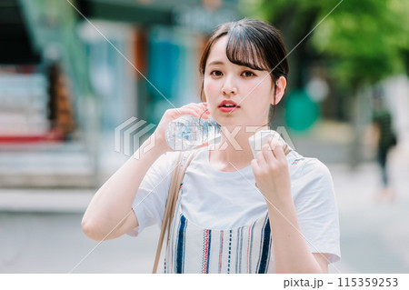 猛暑に耐えペットボトルで体を冷やす若い女性 115359253