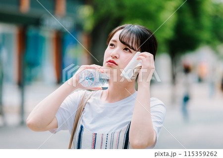 猛暑に耐えペットボトルで体を冷やす若い女性 115359262