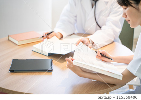 勉強する看護師と医者の手元 115359400