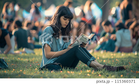 model sitting on the grass, engrossed in a book amidst the summer music festival chaos 115360371