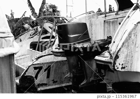 Old and rusty motor boats on a landfill surrounded by tropical forest Old and rusty motor boats on a landfill surrounded by tropical forest 115361967