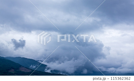 雨の日の山頂を、覆いかぶさりながら流れていく雨雲 雨の日の山頂を、覆いかぶさりながら流れていく雨雲 115362362