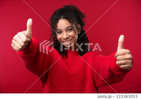 Happy emotions concept. Positive and beautiful young woman laughs poisitively looks aside with carefree face expression wears casual red sweater isolated over red studio background. 115363053