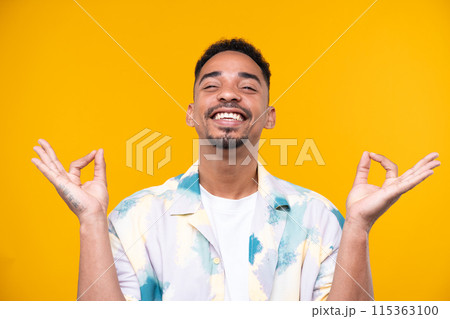 Emotional young black guy in casual raising fists up studio background, celebrating success, happy handsome african american millennial man sharing good emotions. 115363100