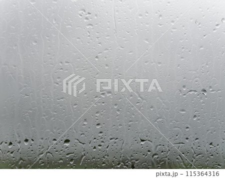 A close-up of a window pane speckled with water droplets, hinting at recent rainfall or misty conditions. 115364316