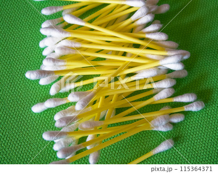 Makeup Accessories. Swabs with yellow handles on a green mat. Makeup Accessories. Swabs with yellow handles on a green mat. 115364371