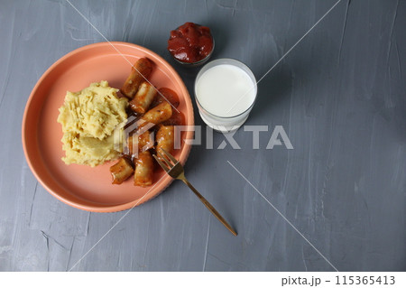 Homemade lunch. Mashed potatoes, sausages, sausages, milk and ketchup, tomato paste on a gray background, top view, copyspace, space for text. Enjoy your meal 115365413