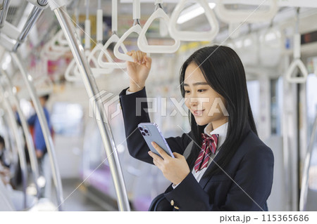 電車の中でスマホを見る女子高校生 115365686