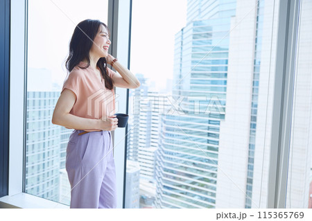 オフィスの窓辺でコーヒーを飲む女性 オフィスの窓辺でコーヒーを飲む女性 115365769