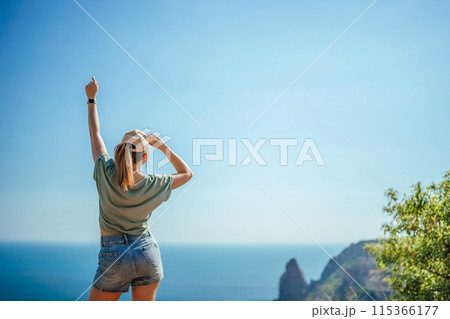 Woman tourist sky sea. Happy traveler woman in hat enjoys vacation raised her hands up Woman tourist sky sea. Happy traveler woman in hat enjoys vacation raised her hands up 115366177