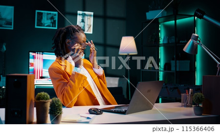 African american student working on her bachelor paper essay at home, writing ideas from online research. Girl exploring digital libraries and academic databases for additional resources. Camera B. 115366406