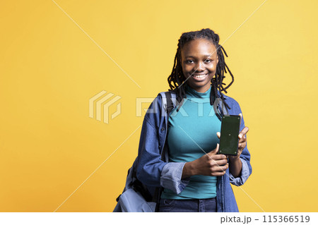 Jolly african american woman presenting smartphone with green screen display, isolated over studio background. Joyous BIPOC person creating promotion with blank copy space mockup phone 115366519