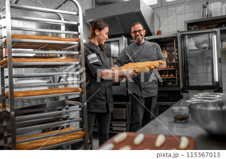 Professional bakers preparing fresh baguette in small bakery Professional bakers preparing fresh baguette in small bakery 115367013