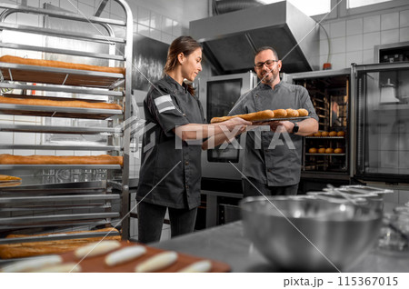 Professional bakers preparing fresh baguette in small bakery 115367015