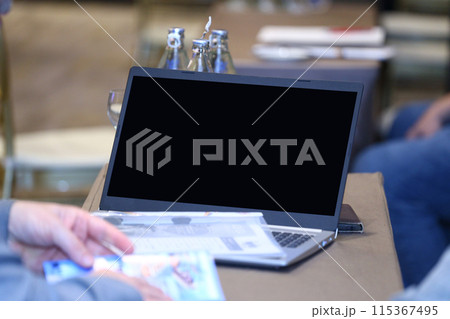 Screen of a blank notebook computer or laptop placed on a conference table. 115367495