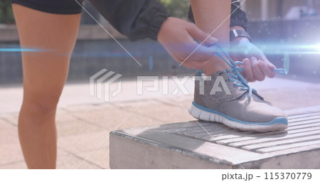 Image of blue light moving over feet of woman in shorts tying running shoe Image of blue light moving over feet of woman in shorts tying running shoe 115370779