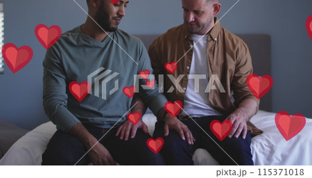Image of red hearts over diverse male couple sitting on bed Image of red hearts over diverse male couple sitting on bed 115371018