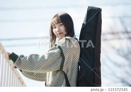 屋外でギターケースを背負った若い女性 屋外でギターケースを背負った若い女性 115372585