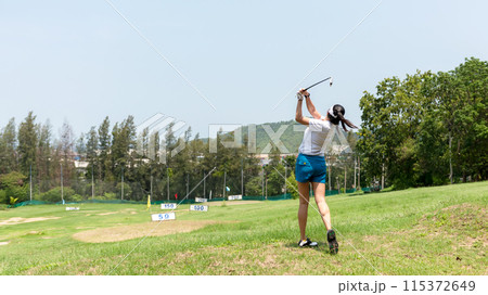 Asian golfer woman swing golf ball practice at golf driving range for relax Asian golfer woman swing golf ball practice at golf driving range for relax 115372649