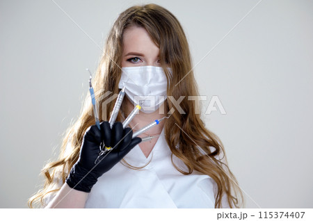 Beautiful woman dentist in a black suit with a white mask with flowing hair holds in her hands scaler and curette Hand stretched forward selective focus bright photo of gorgeous woman Beautiful woman dentist in a black suit with a white mask with flowing hair holds in her hands scaler and curette Hand stretched forward selective focus bright photo of gorgeous woman 115374407