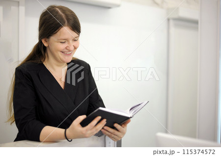 hands of a black notebook with notes notes an interesting book young woman sits at a computer at the reception of a white light office hospital dentistry any computer programmers 115374572