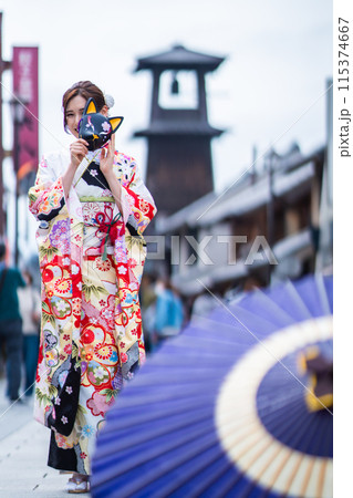 川越の時の鐘の前でポーズをとる振袖の姿の若い女性 115374667