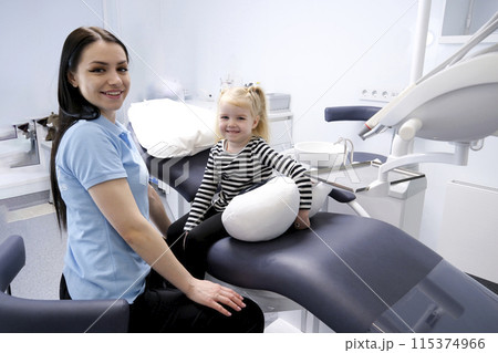 dental office for children young doctor dentist showing little girl dental chair first trip to the dentist happy happiness smile pleasant conversation milk teeth treatment nurse fair-haired girl child dental office for children young doctor dentist showing little girl dental chair first trip to the dentist happy happiness smile pleasant conversation milk teeth treatment nurse fair-haired girl child 115374966