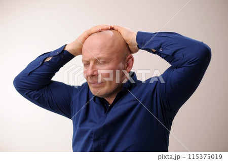 Need medicine for migraine Headache man put his hands on his head and closed his eyes an unpleasant sensation Emotions of an adult handsome bald man A man on a white background in a blue shirt  115375019