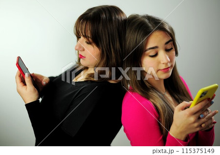 Online communication online learning life on social media life on the internet Mom and daughter turned their backs on each other. They look at their phones. They are busy. Write text messages 115375149
