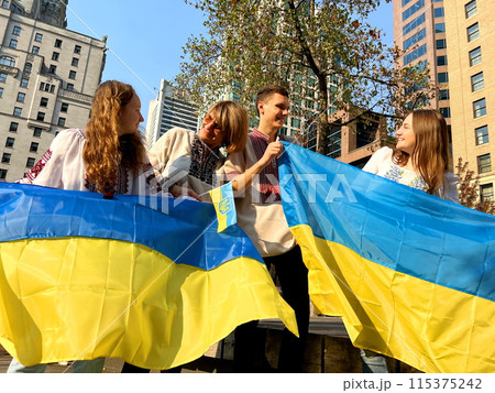 four Ukrainian people in embroidered shirts stand on square with flags Ukraine look at each other happily end of war peace in Ukraine return of emigrants refugees family reunited three women one guy four Ukrainian people in embroidered shirts stand on square with flags Ukraine look at each other happily end of war peace in Ukraine return of emigrants refugees family reunited three women one guy 115375242