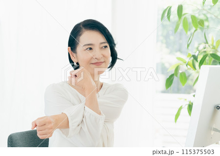 パソコンの前でストレッチをする女性 115375503