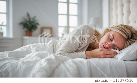 Portrait of a sick or tired woman lying in a white bed at home. 115377510