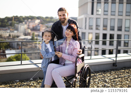 Young man and daughter take care of mother in wheelchair. 115379191