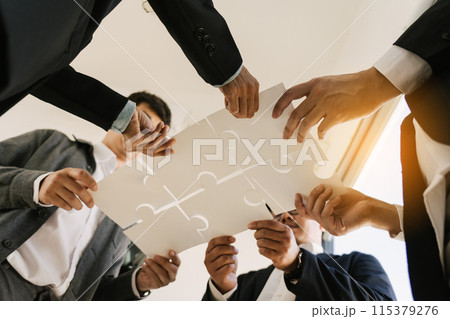 The concept of teamwork and partnership. Businessman's hands putting together puzzle pieces in the office and join together in a jigsaw puzzle team. Charity. Volunteers. Business unity as a team. 115379276