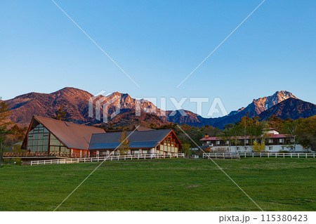 早朝の清里高原から朝日を浴びる八ヶ岳連峰を望む　春季 115380423