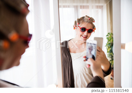 Portrait of beautiful young overweight looking at mirror, having fun. taking selfie with smartphone. 115381540