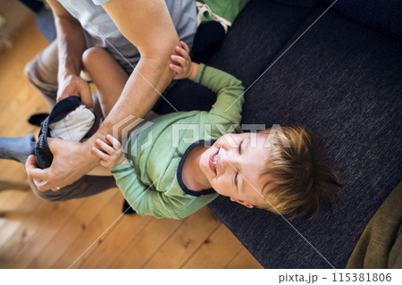Father trying to put clothes on his toddler son, laughing. Hard work. Father trying to put clothes on his toddler son, laughing. Hard work. 115381806