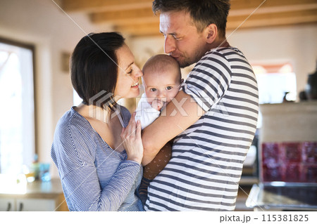 Happy parents holding and playing, kissing small baby, carrying him around house. Unconditional paternal love, family moment. Happy parents holding and playing, kissing small baby, carrying him around house. Unconditional paternal love, family moment. 115381825