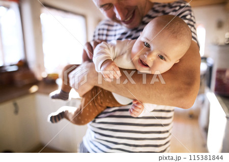 Handsome dad holding small baby, carrying him around house. Unconditional paternal love, father's Day concept. 115381844