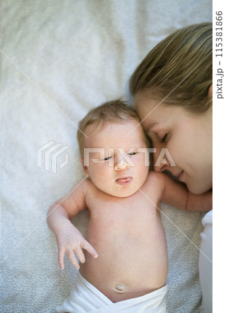 New mom lying on bed by newborn baby girl. Unconditional paternal love, idyllic family moment. New mom lying on bed by newborn baby girl. Unconditional paternal love, idyllic family moment. 115381866